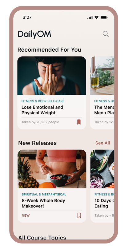 Mobile app screen of DailyOM showing 'Recommended For You' courses including 'Lose Emotional and Physical Weight' with a woman touching her nose, and 'New Releases' featuring '8-Week Whole Body Makeover!' with a person eating a healthy meal.